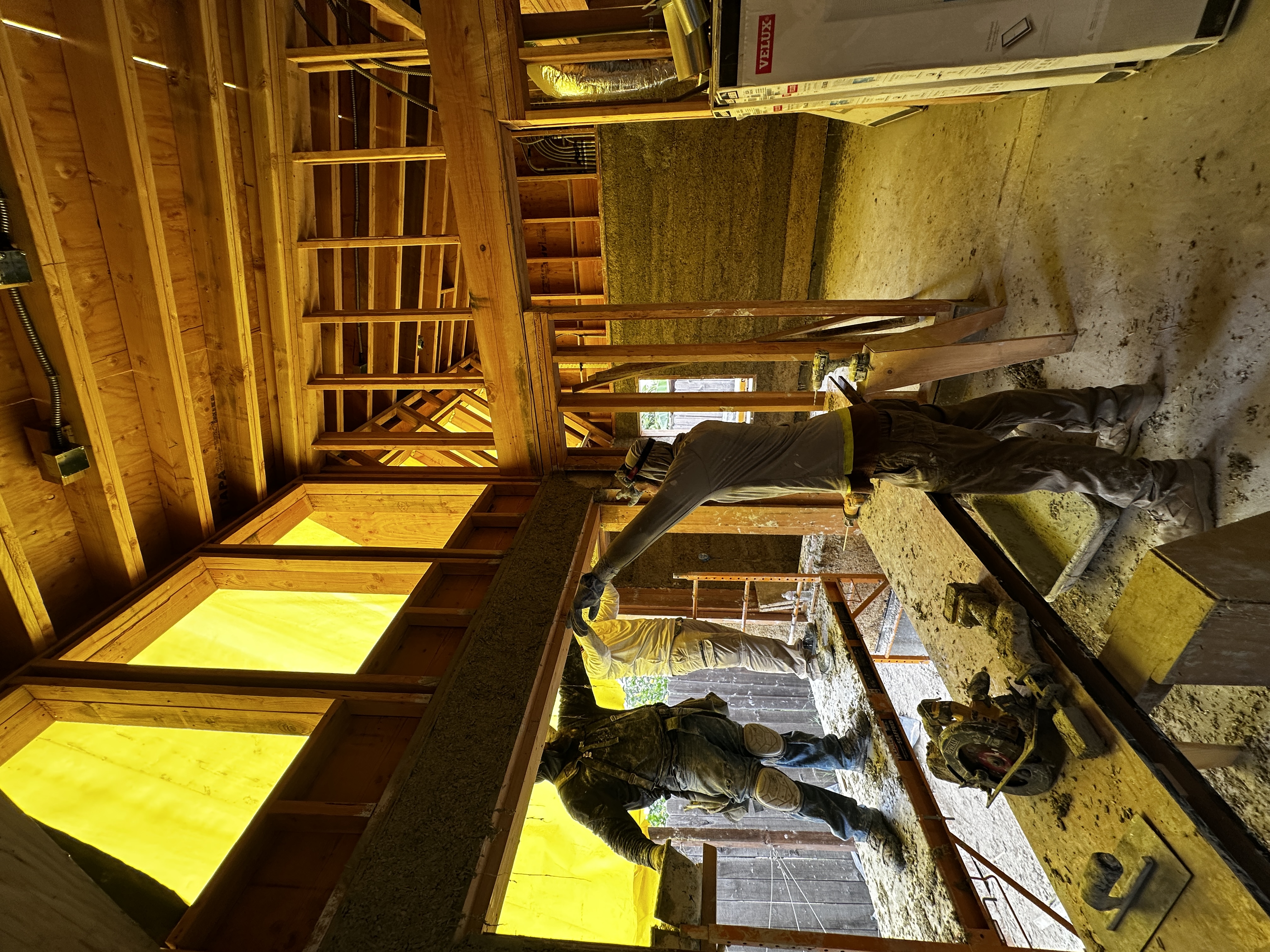 Workers installing hempcrete with skylights above